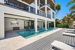 A modern two-story house with a swimming pool, outdoor seating, and a balcony. - Bimini Sunrise (Anna Maria)