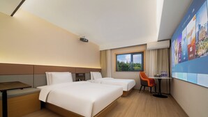 Ein Hotelzimmer mit zwei Betten, einem Schreibtisch, einem Stuhl, einem Fernseher und einem Fenster mit Blick.