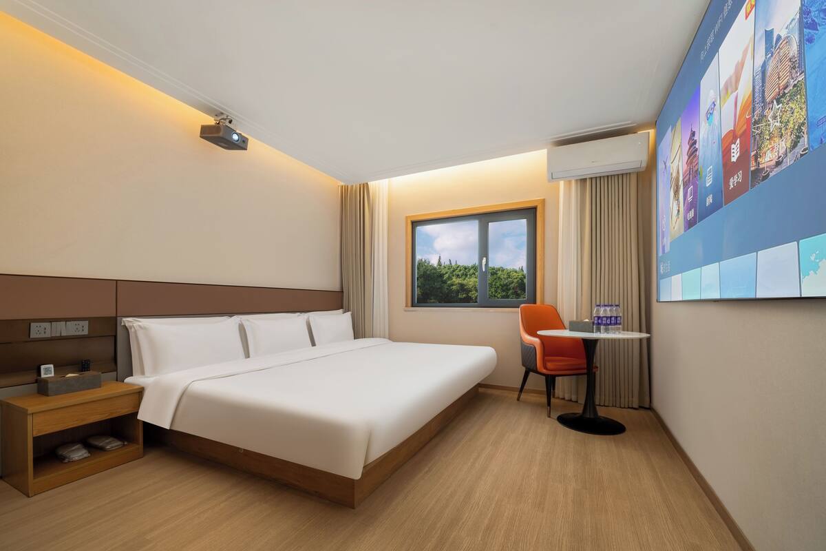 Habitación de hotel con cama, escritorio, silla, ventana con vistas y pared decorada con imágenes.