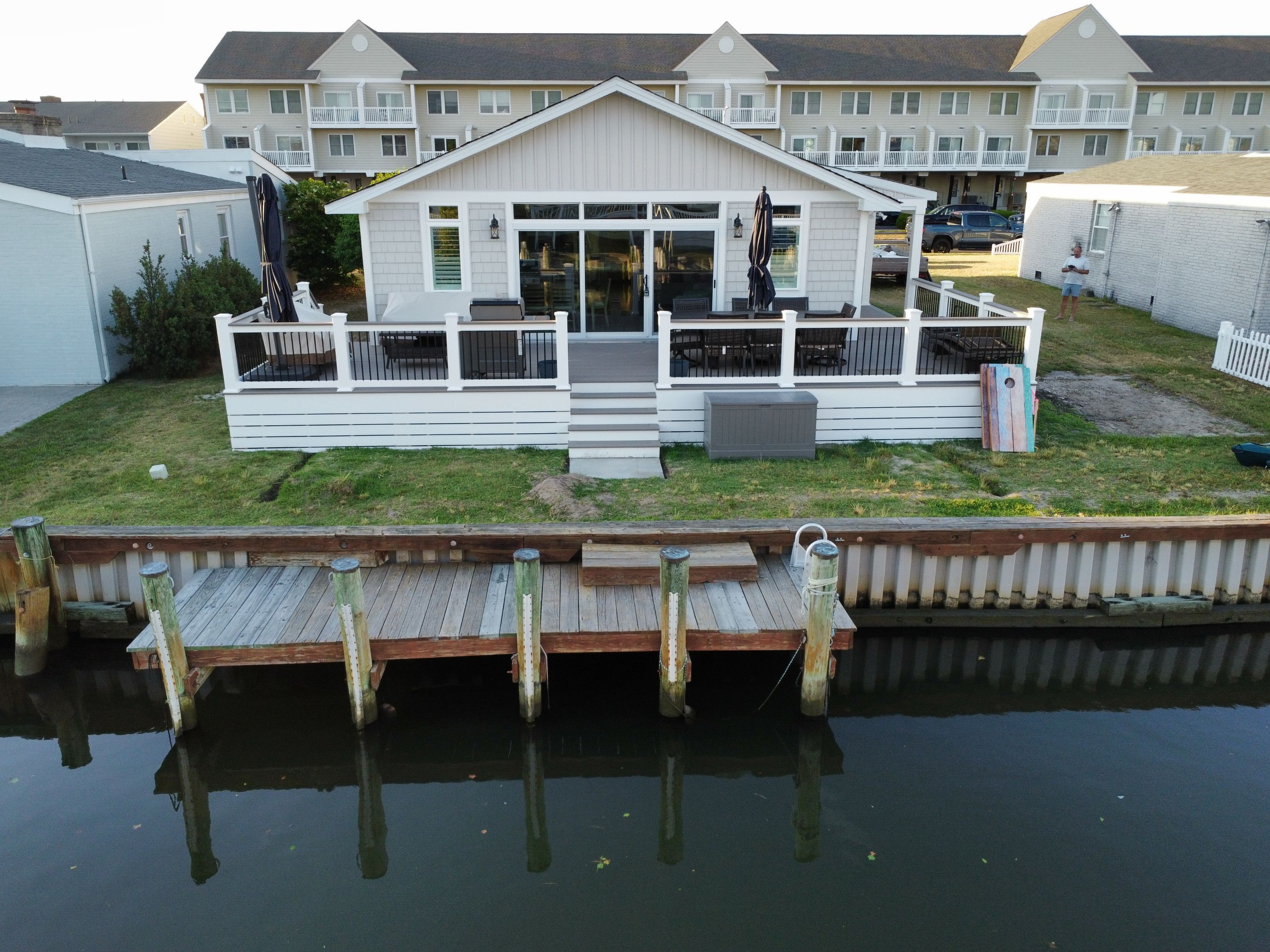 A waterfront property with a dock, a covered patio, and a large building with multiple balconies.