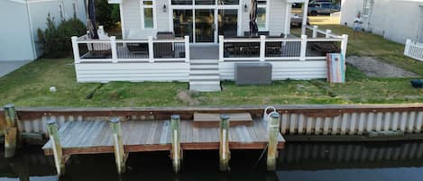A waterfront property with a dock, a covered patio, and a large building with multiple balconies.