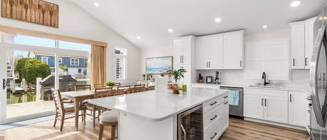 A modern kitchen with white cabinetry, a central island, and a view to the outside.