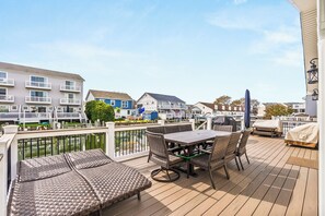 A deck with outdoor furniture, a view of a marina, and residential buildings in the background. - Newly Renovated Bayside Retreat - Steps to the Beach (Ocean City)