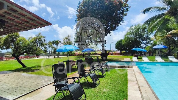 A pool area with lounge chairs, umbrellas, and a clear sky. - Flats Beira-rio com Espaco Gourmet Completo (Tamandaré)
