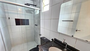 A bathroom with a glass shower enclosure, a toilet, a sink, and a mirror. - Flats Beira-rio com Espaco Gourmet Completo (Tamandaré)