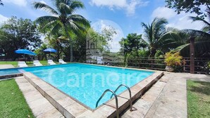 A rectangular swimming pool with clear blue water, surrounded by a tiled deck and a metal railing. - Flats Beira-rio com Espaco Gourmet Completo (Tamandaré)