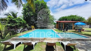 A swimming pool with lounge chairs, a stone structure, and a building with a red roof. - Flats Beira-rio com Espaco Gourmet Completo (Tamandaré)