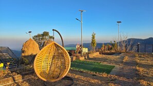 Uma construção com telhado de palha, um assento esférico trançado e luminárias solares em um cenário rural.