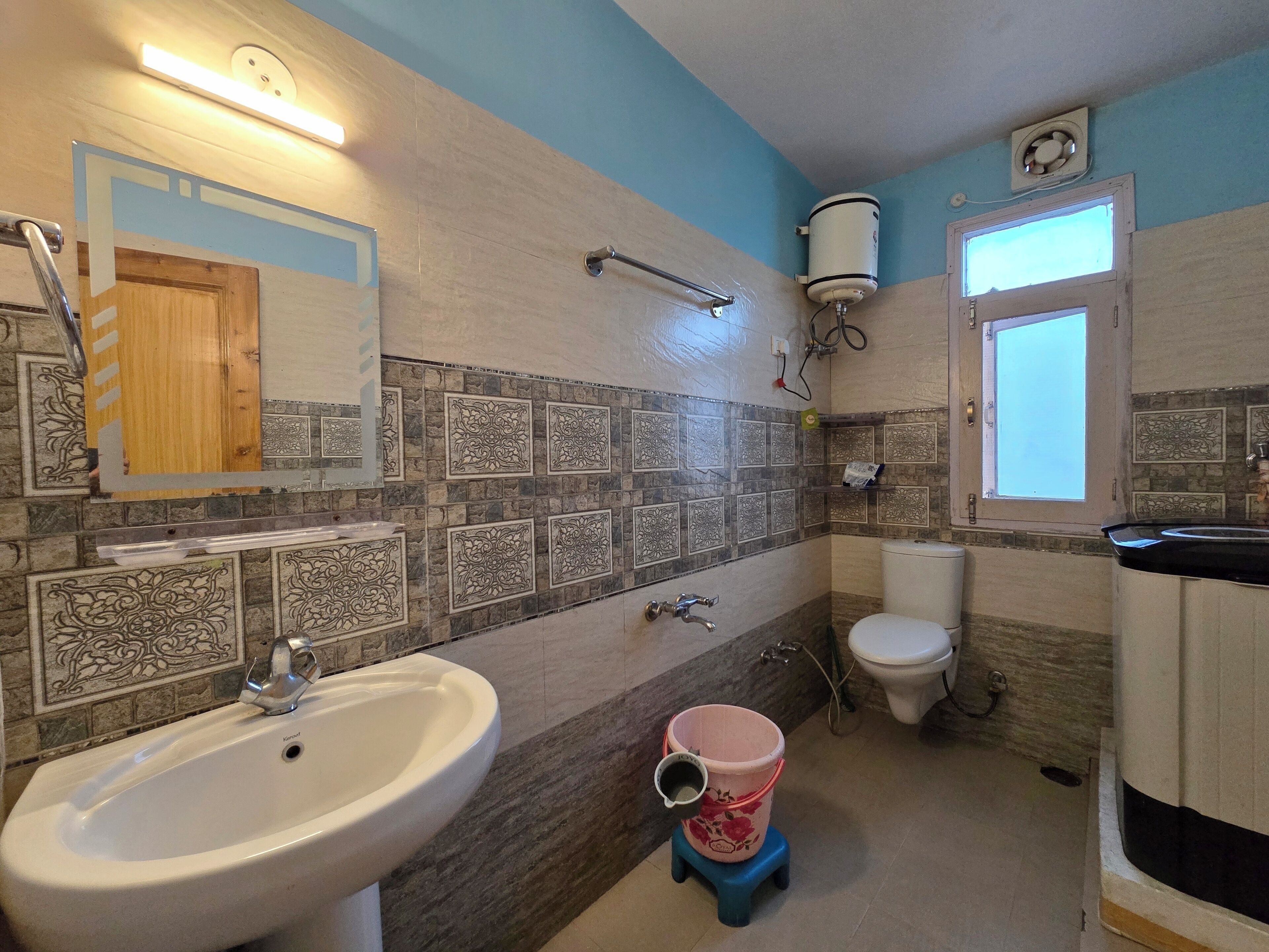 Baño con lavamanos, inodoro y zona de ducha.
