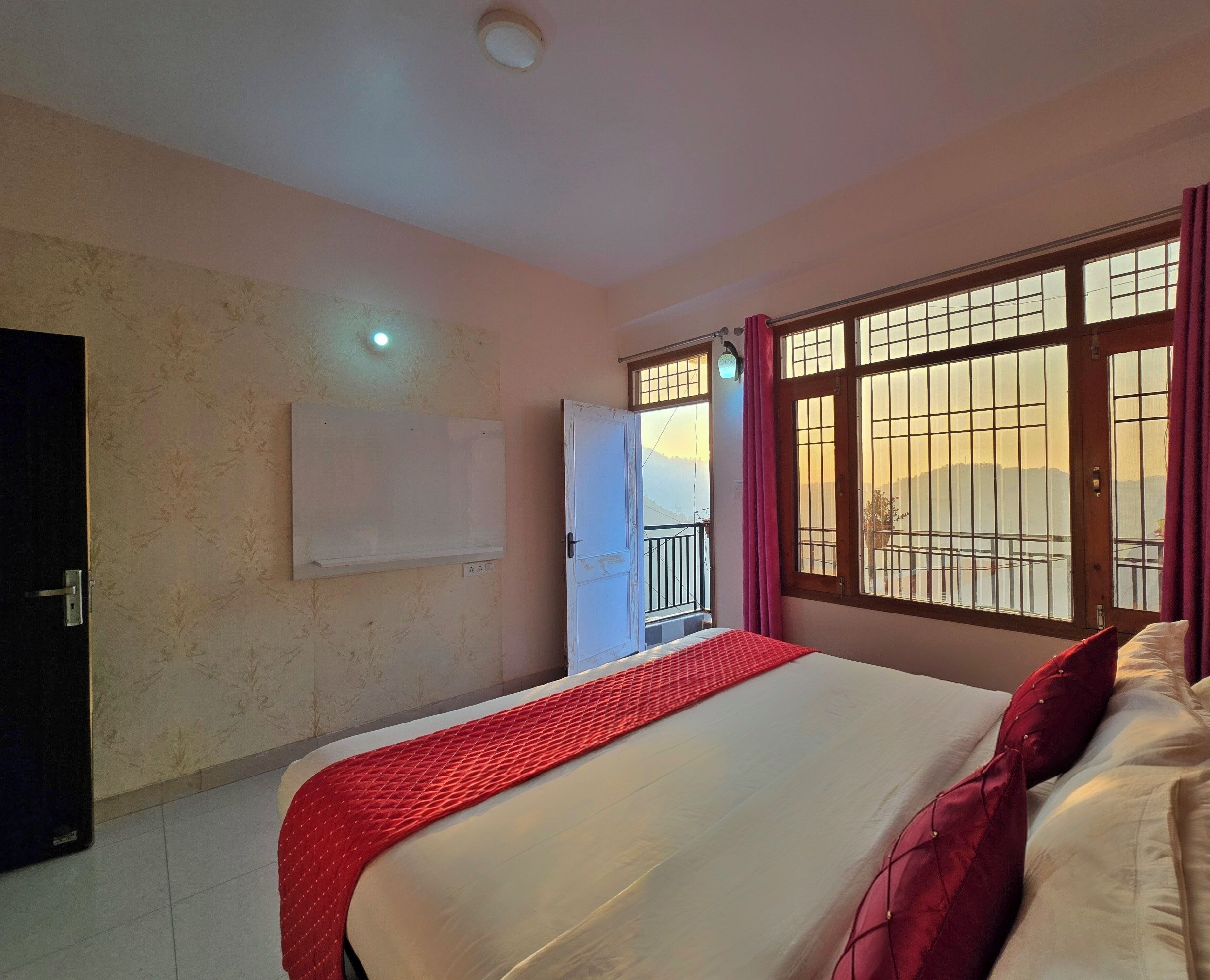 Una habitación de hotel con cama, ventana con rejas, puerta y televisor montado en la pared.