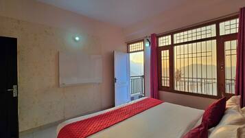 Una habitación de hotel con cama, ventana con rejas, puerta y televisor montado en la pared.