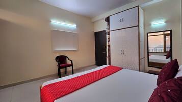 A hotel room with a bed, a wardrobe, a chair, and a mirror.