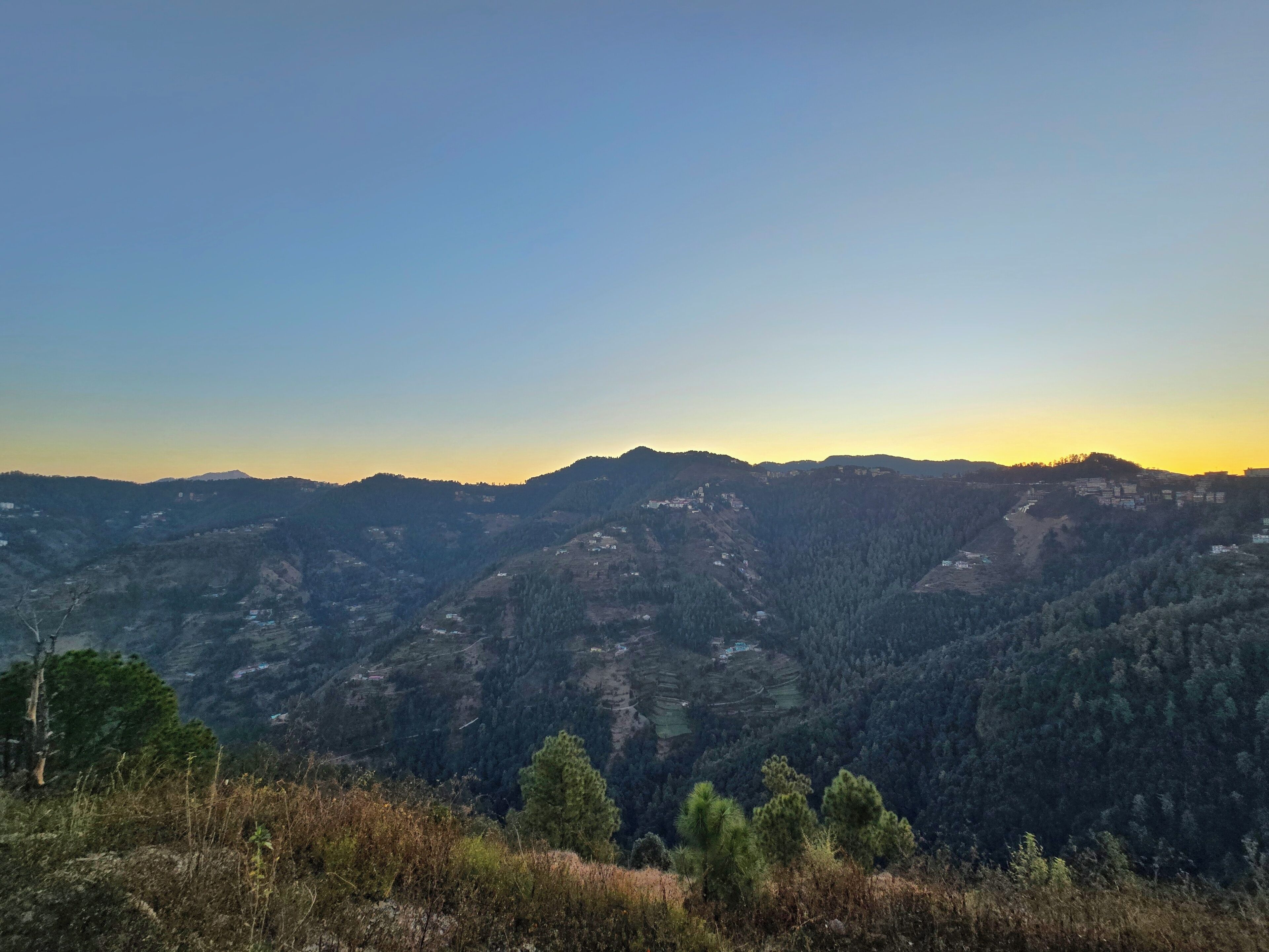 Un paisaje montañoso con campos en terrazas y edificios dispersos.