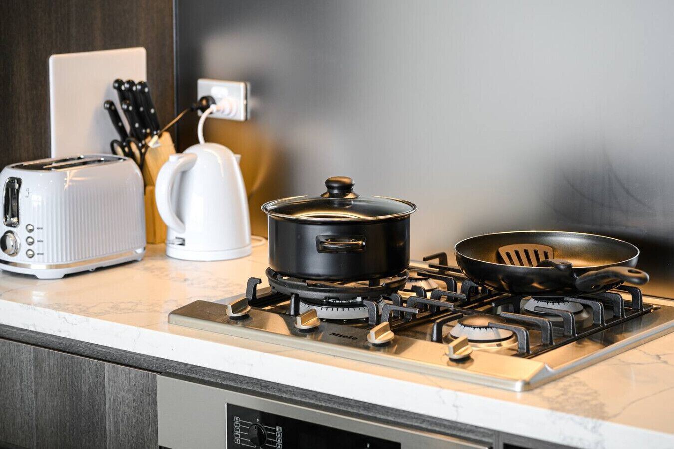 A kitchen with a gas stove, a toaster, and a kettle.