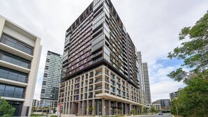 Un immeuble moderne de grande hauteur, doté de nombreux balcons, de grandes fenêtres et d’une façade combinant verre et béton.