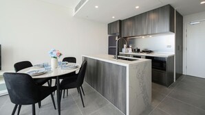 Une cuisine moderne dotée d’un îlot central, de meubles en bois foncé et d’un plan de travail blanc.