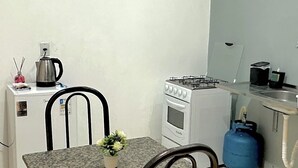 Cocina compacta con estufa a gas, horno y refrigerador pequeño.