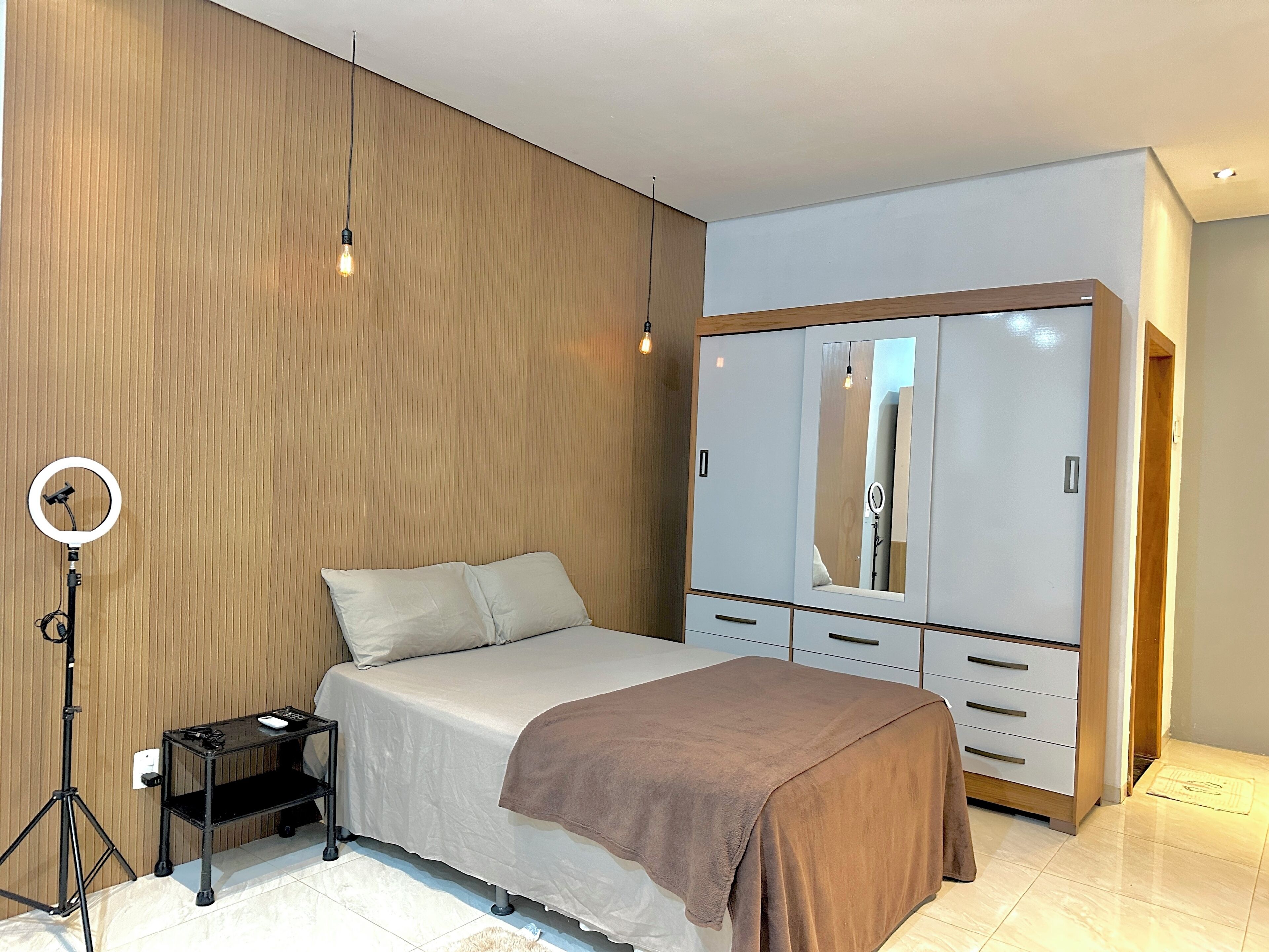 Une chambre avec un lit, une armoire, un anneau lumineux et une petite table.