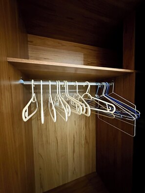 A wooden closet with a metal drying rack holding several white hangers.