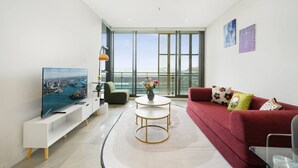 Ein modernes Wohnzimmer mit Fernseher, Sofa und Balkon mit Stadtblick.