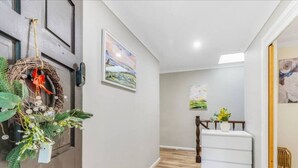A hallway with a wooden door, a white console table, and a painting on the wall. - 4BR Castle Hill Home | Garage | Near Mall & Park (Castle Hill)