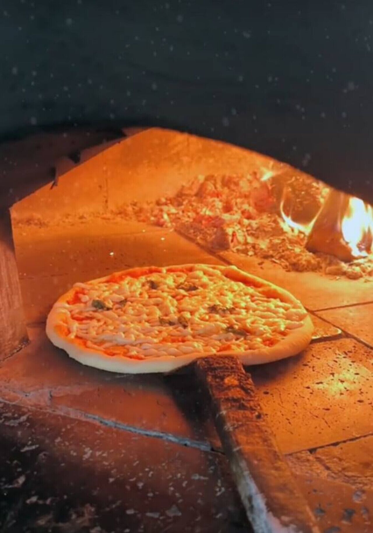 Un four à pizza dans lequel deux pizzas sont en train de cuire.