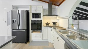 Eine moderne Küche mit Edelstahl-Kühlschrank, eingebautem Backofen, Mikrowelle und Spüle mit modernem Wasserhahn.