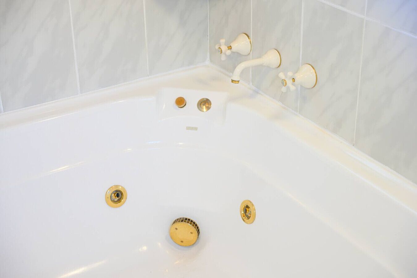 Una bañera blanca con accesorios dorados y un tapón.