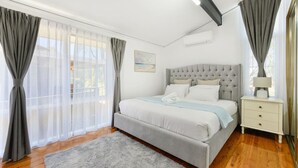 Ein Schlafzimmer mit Bett, Nachttisch, Lampe und einem Fenster mit Vorhängen.