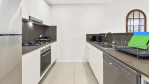 Cozinha moderna com eletrodomésticos de aço inoxidável, máquina de lavar louça e janela com vista.