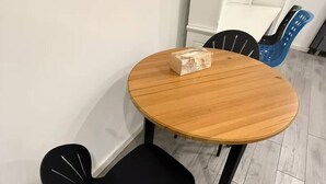 A round wooden table with a black chair, a blue chair, and a white shelf in the background. - Burwood Studio 1Br Near Train Station/Shopping (Burwood)