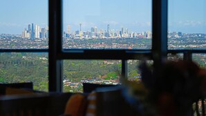 A view from a window overlooking a cityscape with tall buildings and a distant tower.