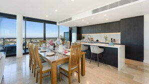 A modern kitchen with a central island, dark cabinetry, and a large window overlooking a cityscape.
