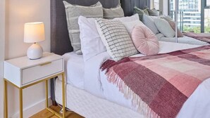 Une chambre moderne avec un grand lit, une table de chevet avec une lampe et un grand miroir qui reflète la pièce.
