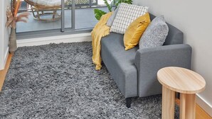 Un salon moderne avec un canapé gris, une petite table ronde en bois et un fauteuil en osier.