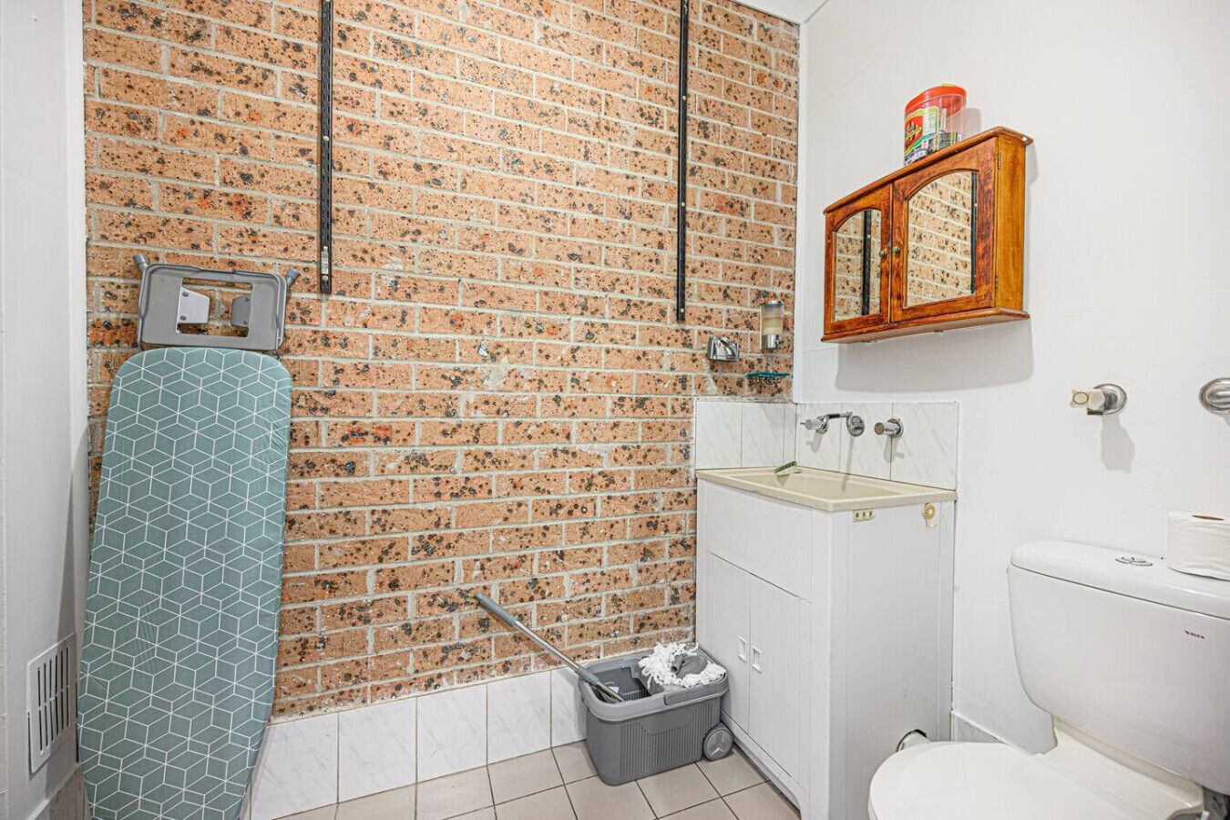 Une salle de bain avec un mur en briques, une douche, un lavabo et des toilettes.