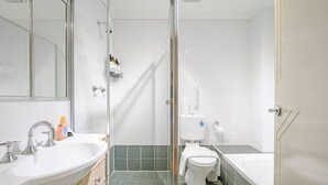 Une salle de bain moderne avec une douche à parois de verre, un lavabo blanc et une baignoire.