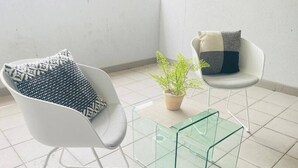 Ein stilvolles Zimmer mit weißem Stuhl, Glastisch und einem Topf mit Pflanze.
