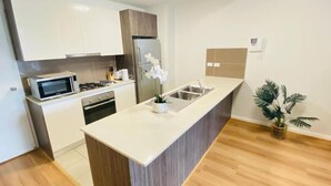 Eine moderne Küche mit weißen Schränken, einem Edelstahlkühlschrank, einer Mikrowelle und einem Spülbecken.