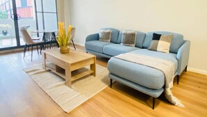 Ein modernes Wohnzimmer mit einem blauen Sofa, einem Holztisch und einem großen Fenster.