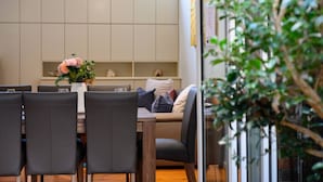 Ein moderner Essbereich mit einem Holztisch, schwarzen Stühlen und einer Blumenvase.
