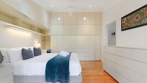 Ein modernes Hotelzimmer mit einem großen Bett, integrierten Regalen und einem an der Wand befestigten Kunstwerk.