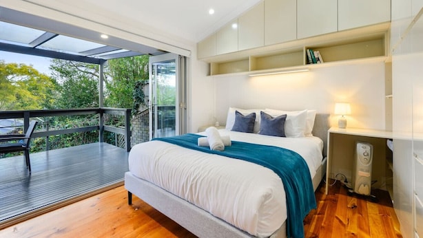 Ein modernes Schlafzimmer mit einem großen Bett, einem Balkon und einem Deckenventilator.