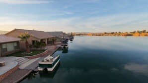 Propiedad frente al agua con muelle, barcos y casas con vista al agua y montañas al fondo.