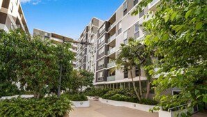 A multi-story residential building with balconies, surrounded by lush greenery and a paved courtyard. - 2BR APT near Train Station/4ppl/Couple/Business (Canterbury)