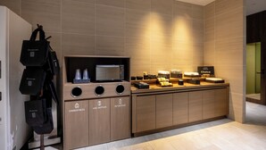 Eine moderne Hotelküche mit Mikrowelle, Kaffeemaschine und verschiedenen Annehmlichkeiten, wie Mülleimer und Wertstoffbehälter.