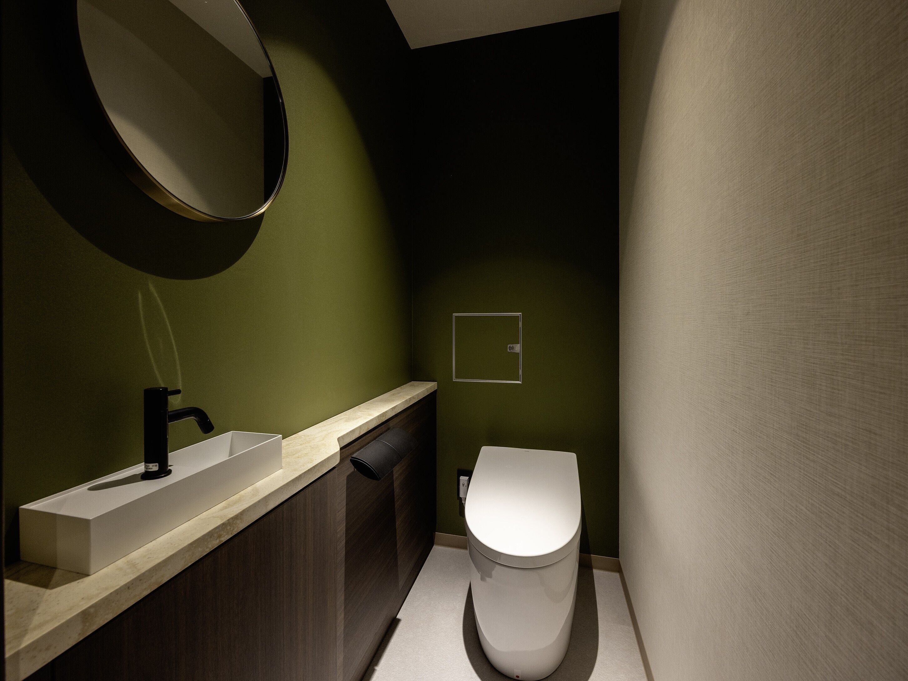 A modern bathroom with a sink, mirror, and toilet.