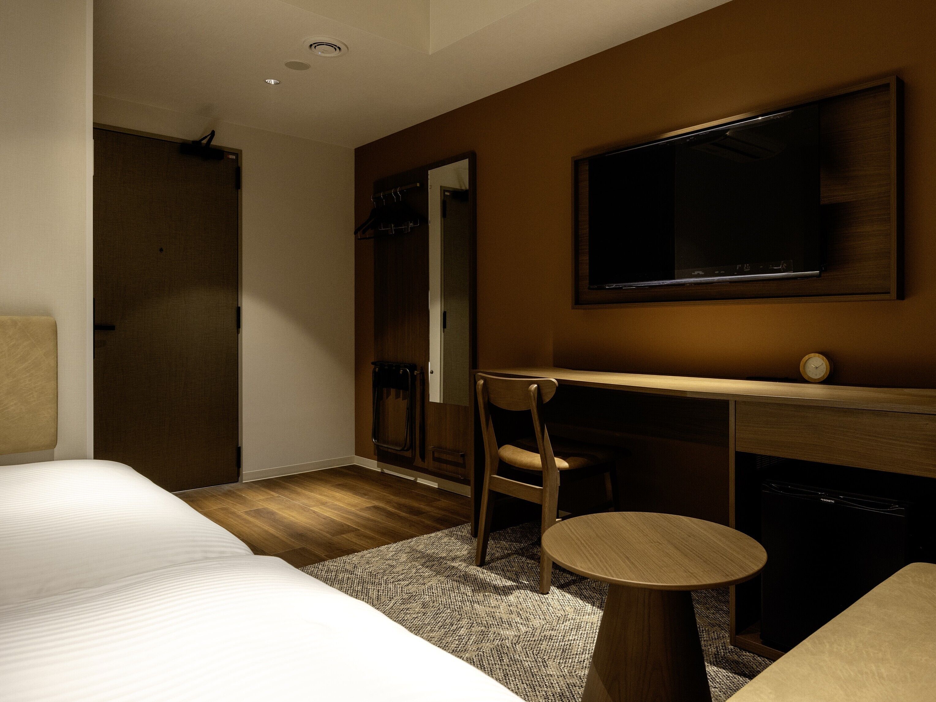 Ein Hotelzimmer mit einem Bett, einem Schreibtisch, einem Sessel, einem Fernseher und einem kleinen Tisch.