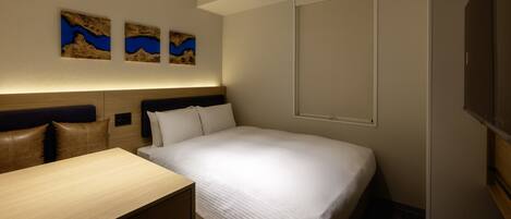 A hotel room with a bed, a desk, and two wall-mounted paintings.