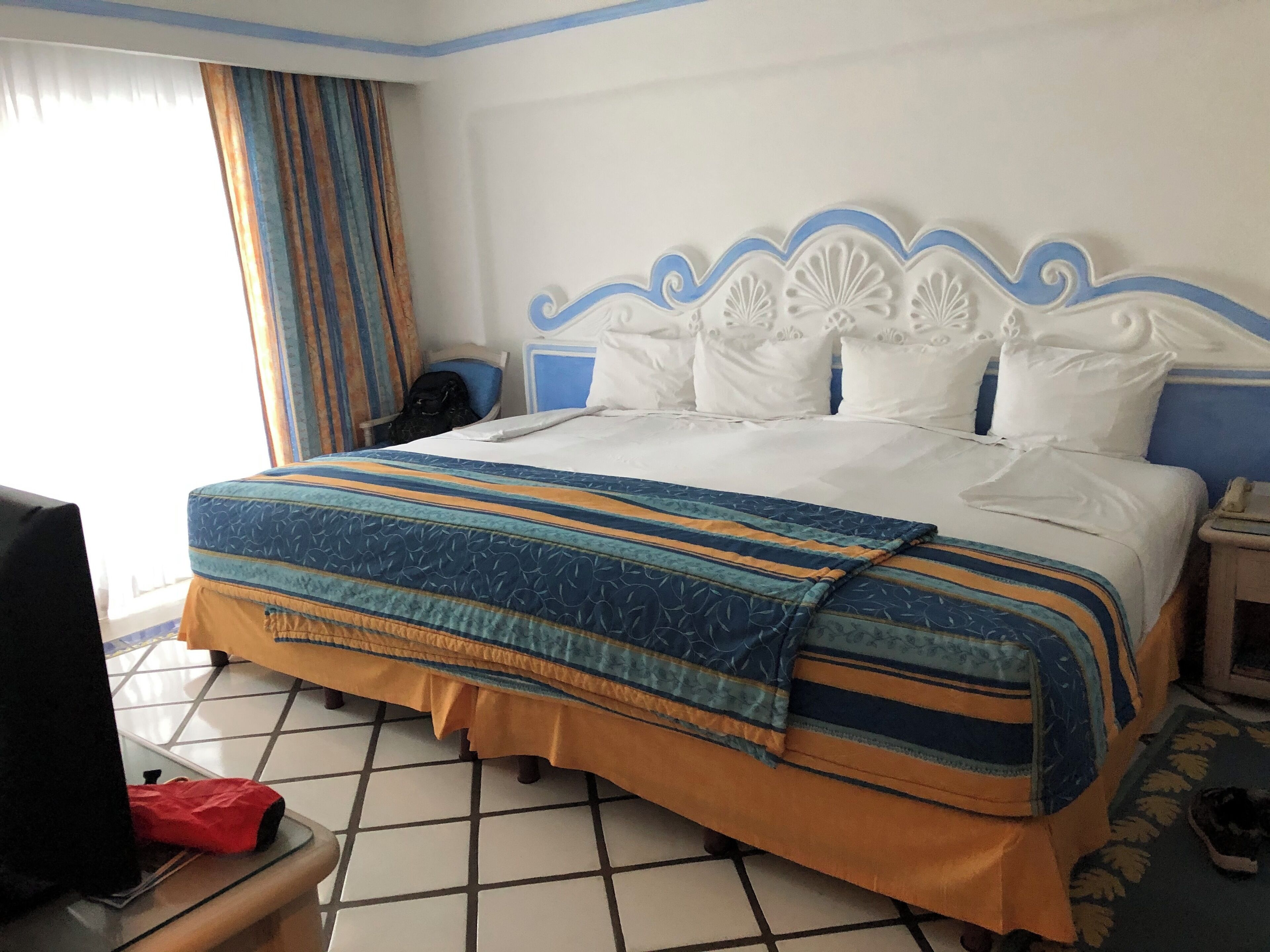 A hotel room with a bed, a television, and a suitcase on the floor.
